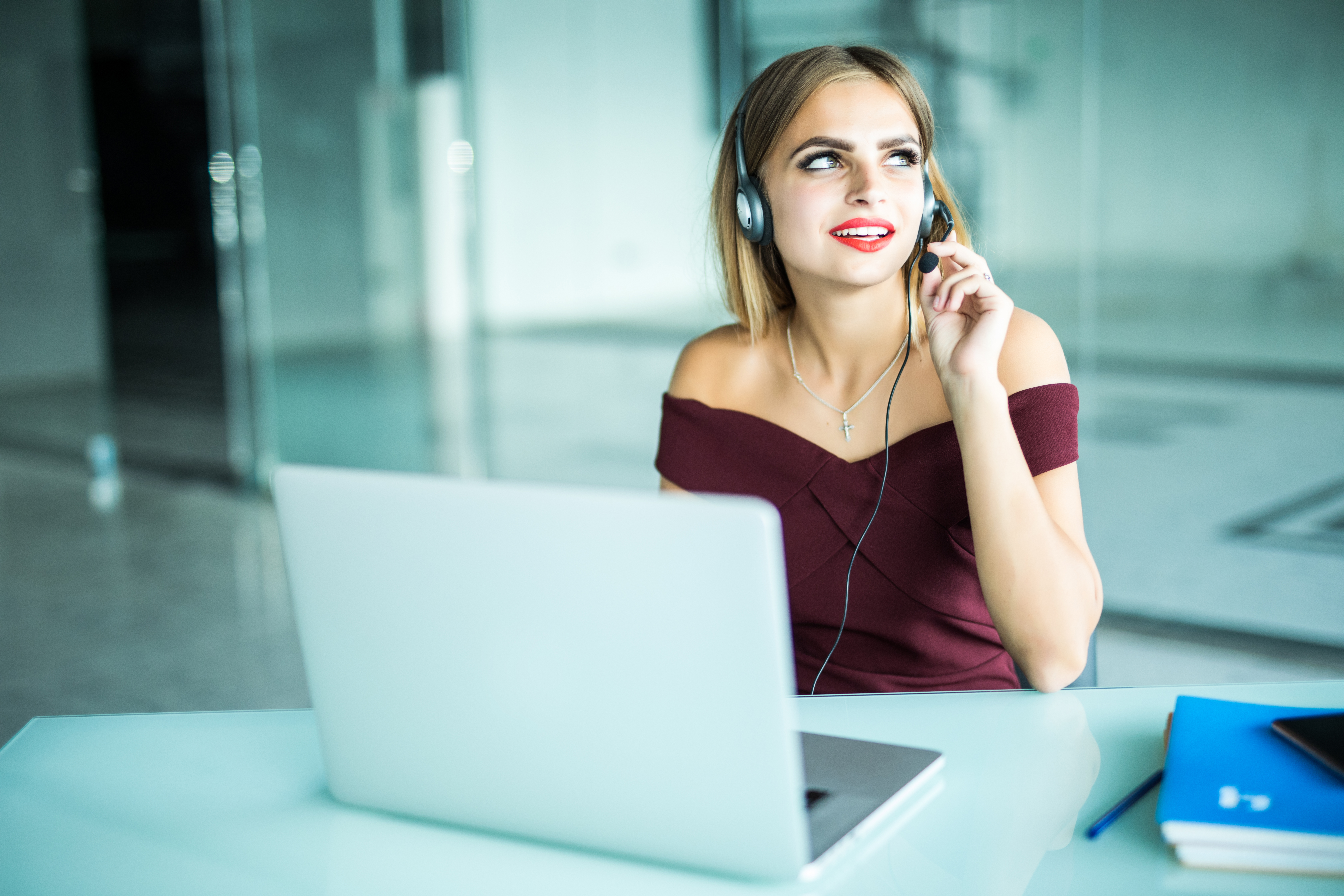 Focused attentive woman in headphones sits at desk with laptop, looks at screen, makes notes, learns foreign language in internet, online study course self-education on web consults client by video